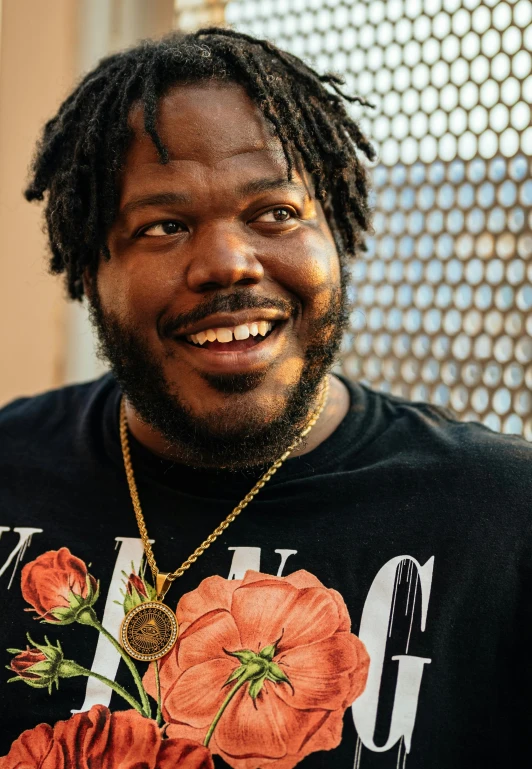 a man with dreadlocks and a flower on his neck