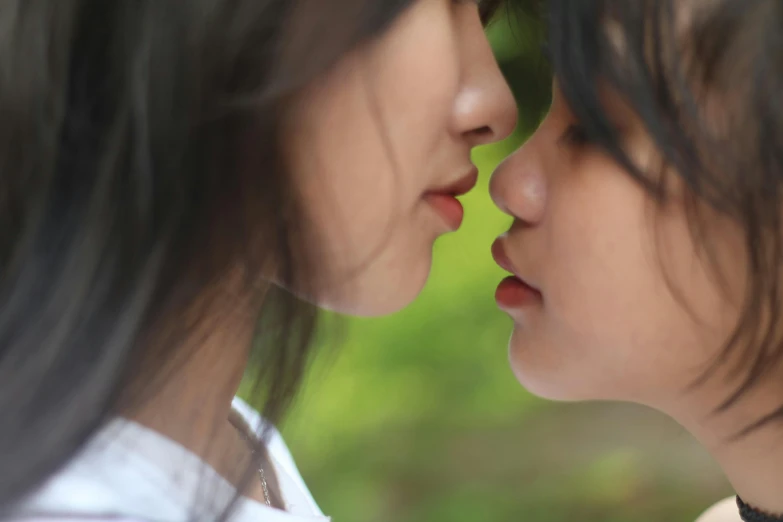 two asian women are kissing with each other