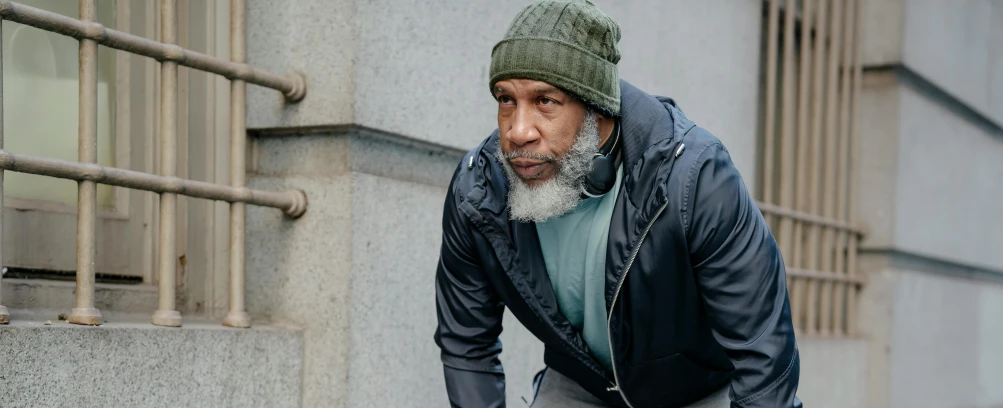 a man in blue jacket leaning against wall on cement ledge