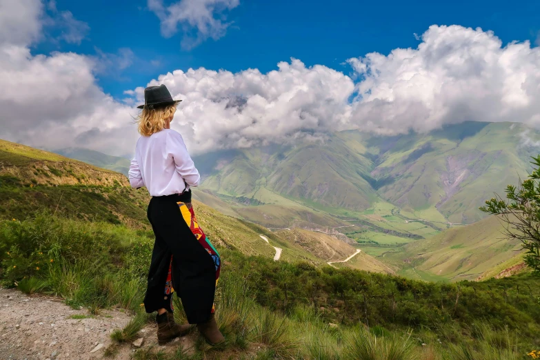 a lady is standing on a hill looking into the valley