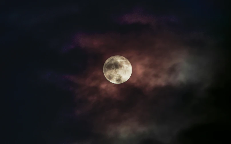 a full moon sitting in the middle of a black sky