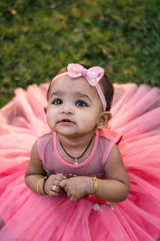 a small child wearing a pink tutu and wearing a tiara