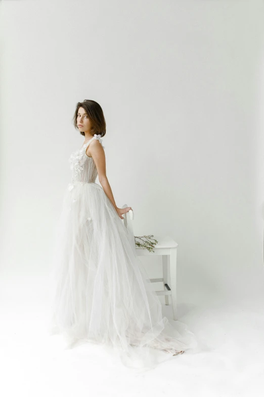 a woman in white dress standing next to table