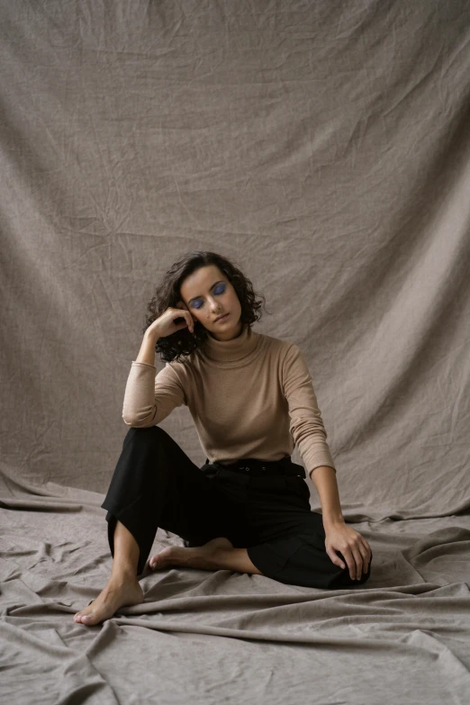 a beautiful woman sitting on a bed holding a cell phone