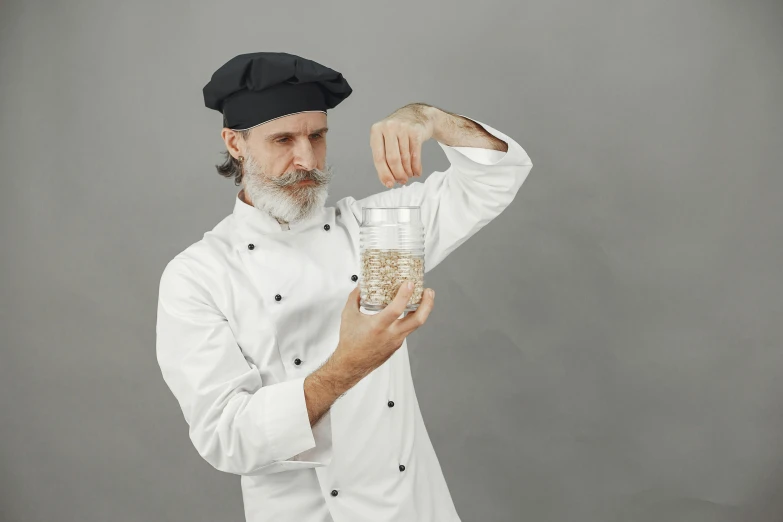 a man wearing a chef hat is holding a glass filled with liquid