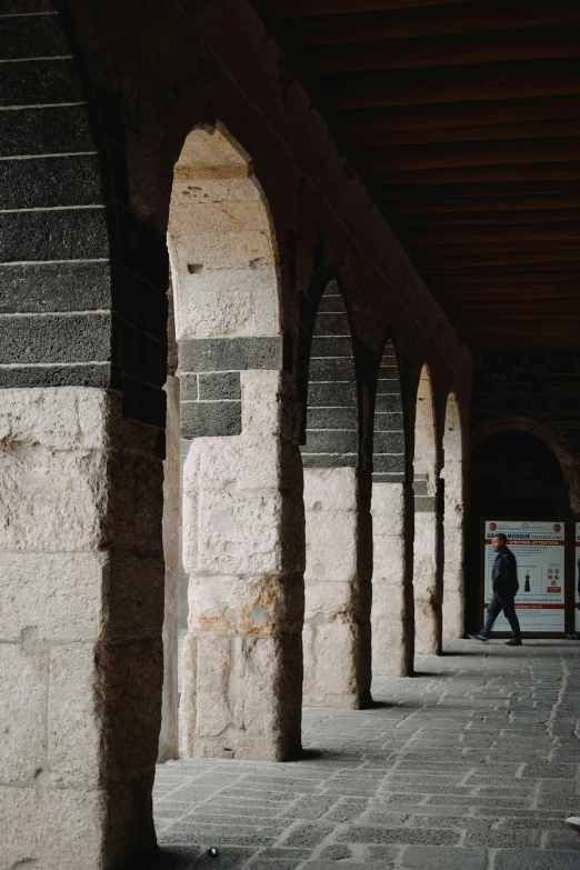 a person walking on an underground walkway near columns