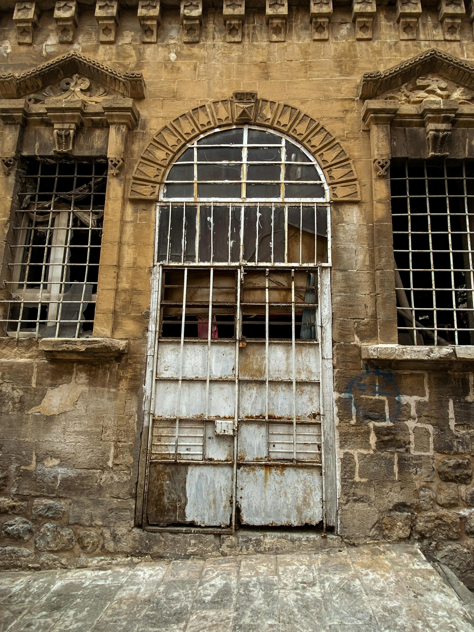 a very dirty old brick building that has windows and bars on the front