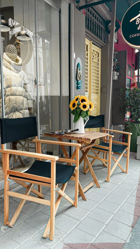 wooden chairs and tables sit outside of the store front