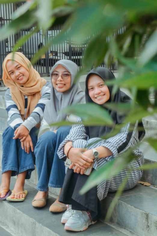 three women on steps one wearing a hijab