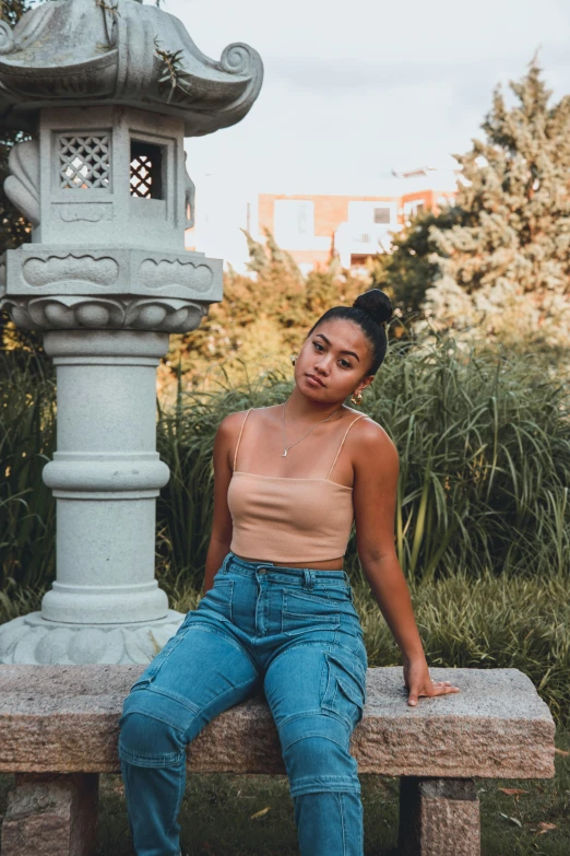 a beautiful young black woman wearing a tan tank top and blue jeans