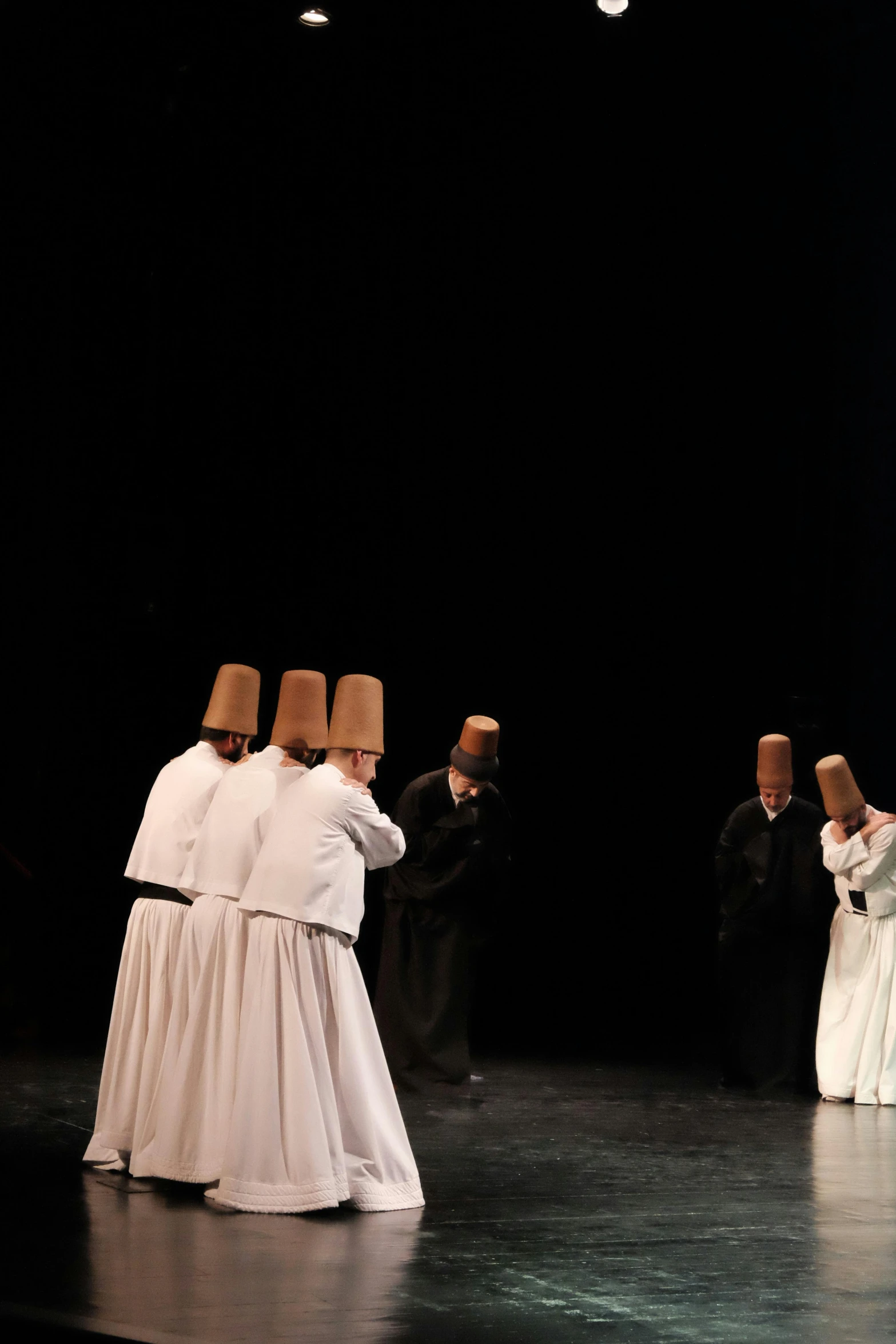 three people standing in a line, one wearing a priest's robes and the other wearing a suit with white cloths