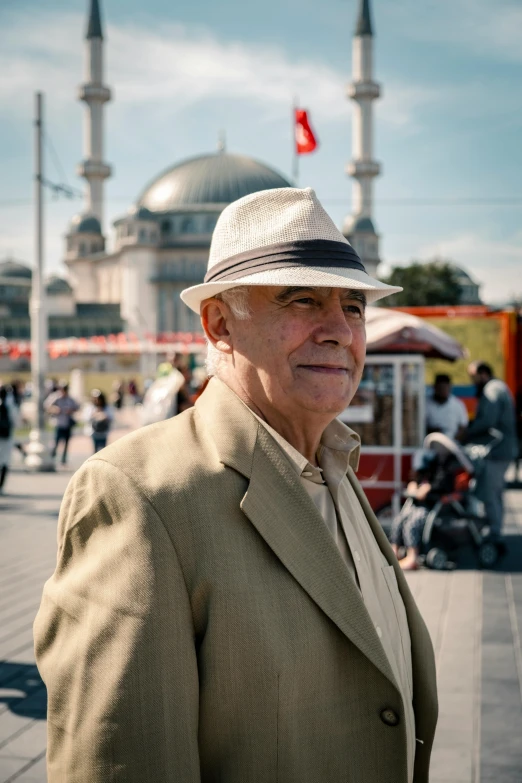 a man wearing a hat standing near a mosque