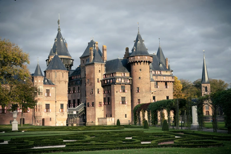 a large castle sits among some greenery on a cloudy day