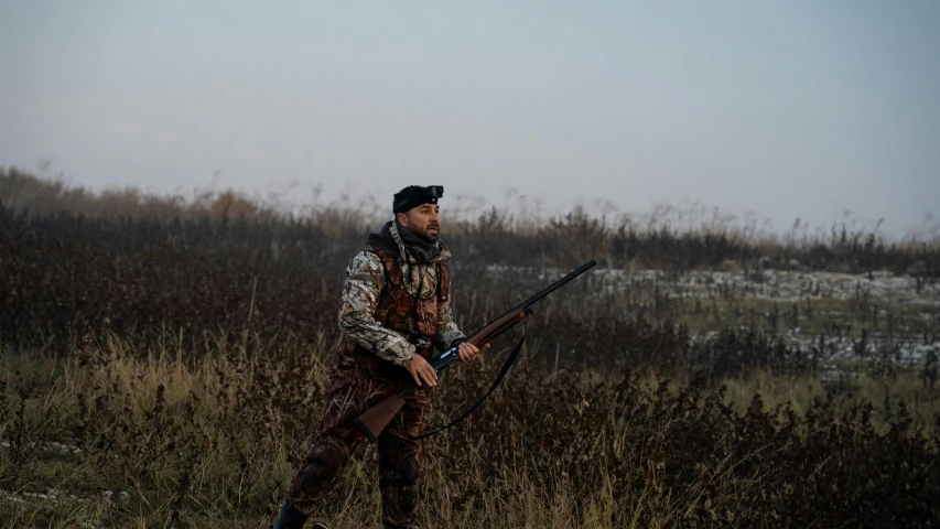 a man holding a hunting sgun in his hand