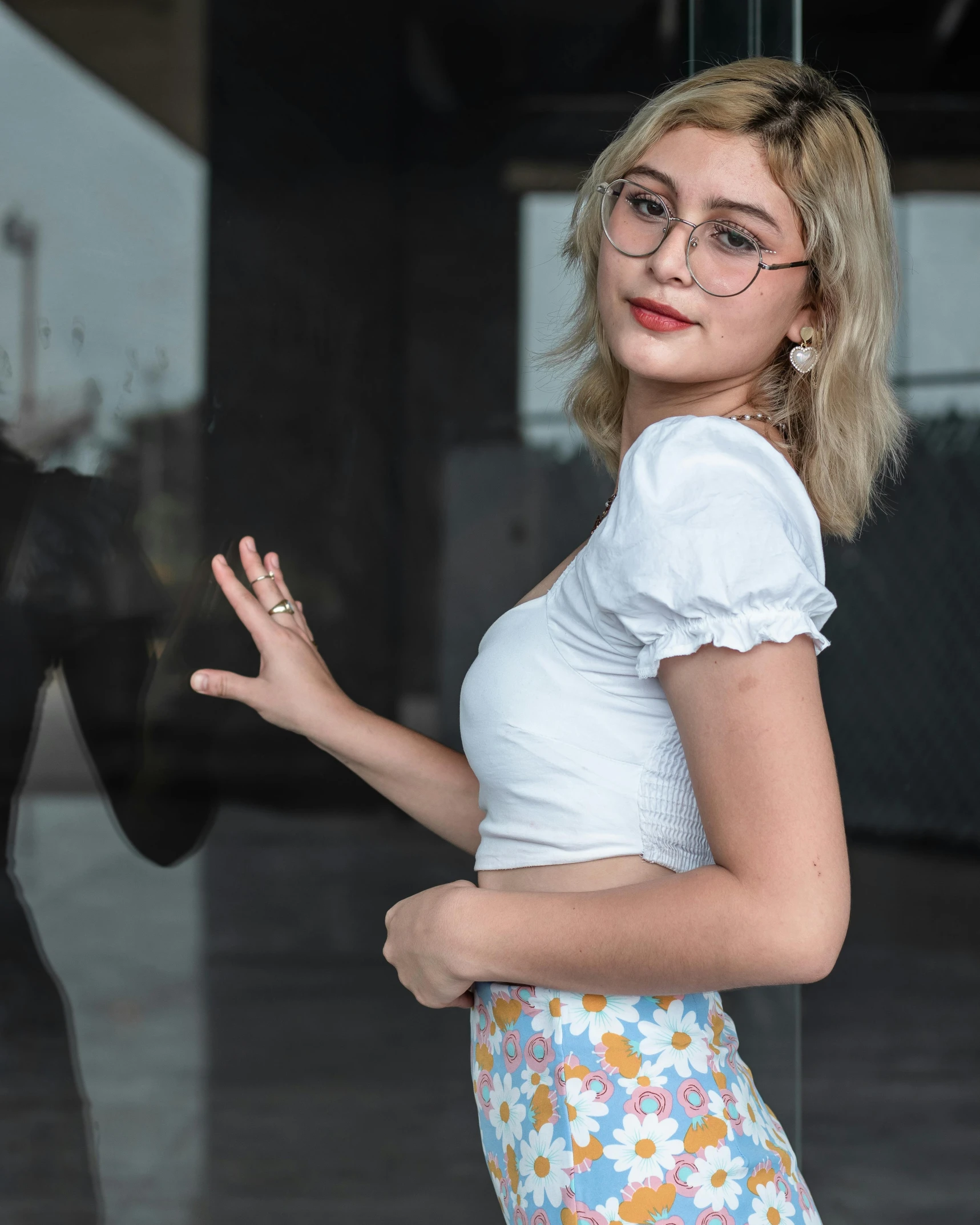 a woman in glasses standing on the sidewalk