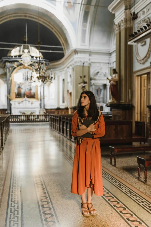 woman in long dress standing in front of pews in a church