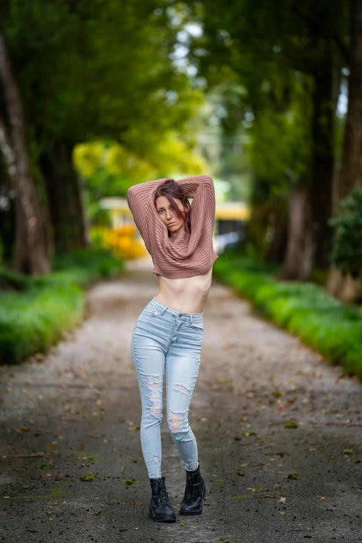 woman dancing with her arms behind her head in the air in the park