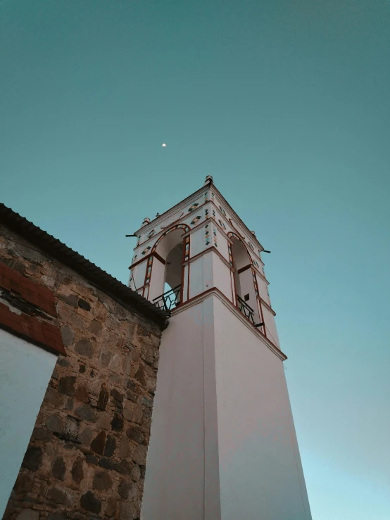 a white clock tower near the side of a brick wall