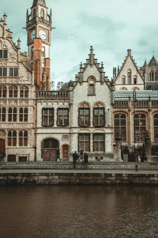 a building with two tall towers next to a body of water