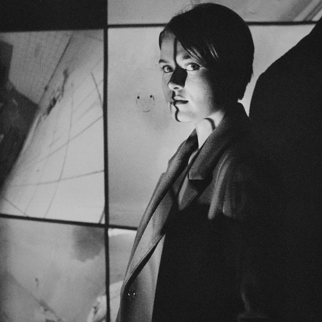 black and white pograph of man standing in front of a wall