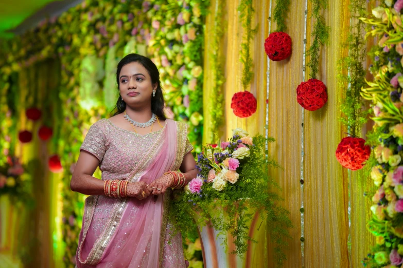 woman in pink sari holding flowers surrounded by flower arrangements