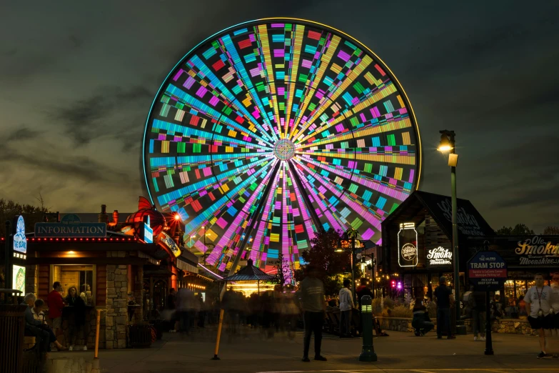 people are walking through an open area with a ferris wheel