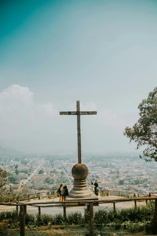 people are at the top of a hill watching a cross