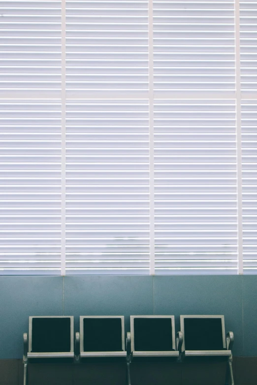 empty seating in front of an empty window with vertical blinds