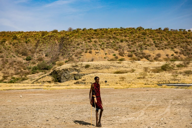 a person stands on the sand in front of a hill