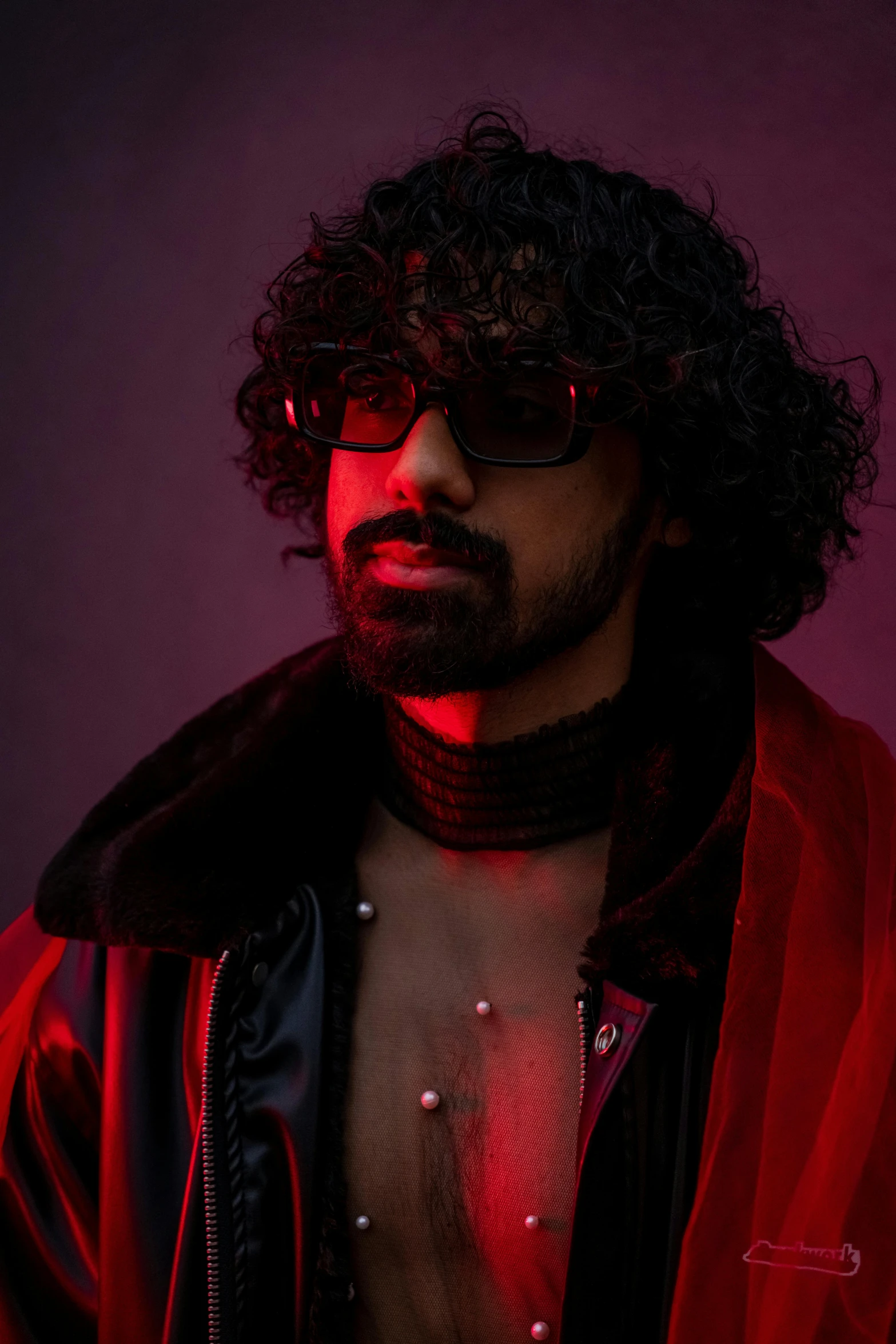 a man wearing shades with a red light behind him