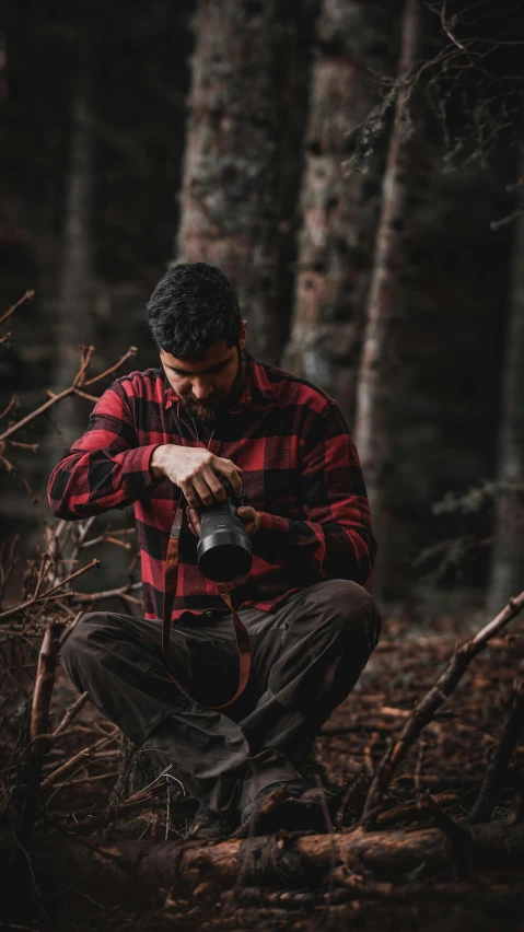 a man in the woods is looking at his digital camera