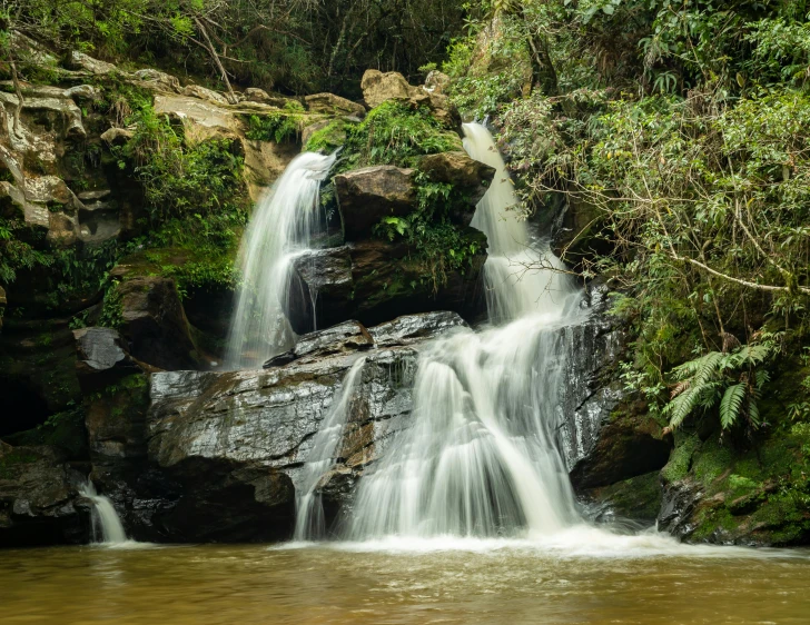 a waterfall surrounded by some jungle with green trees