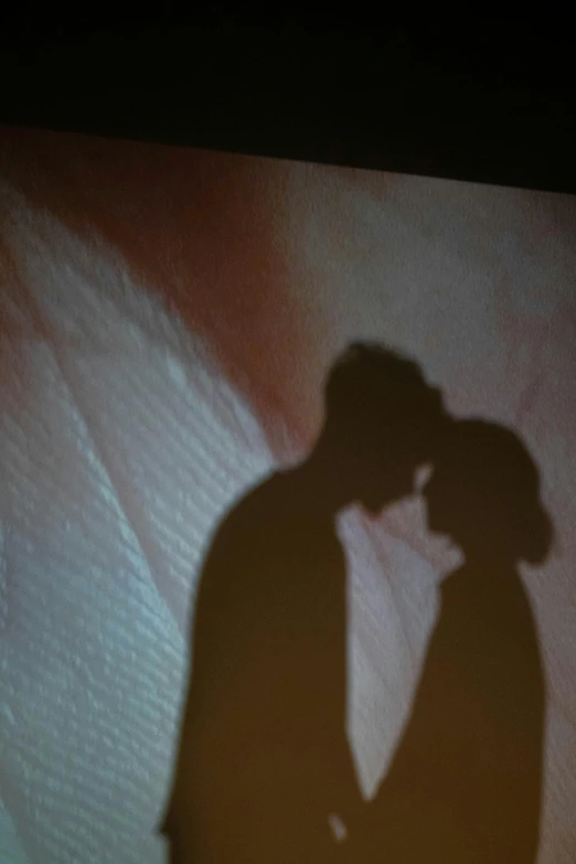 a man standing in front of a screen kissing a woman