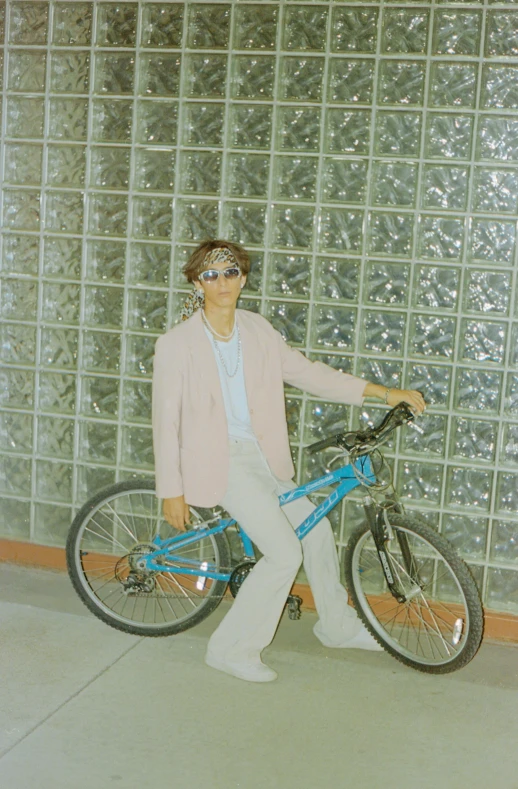 a woman posing with her bicycle by some glass bricks