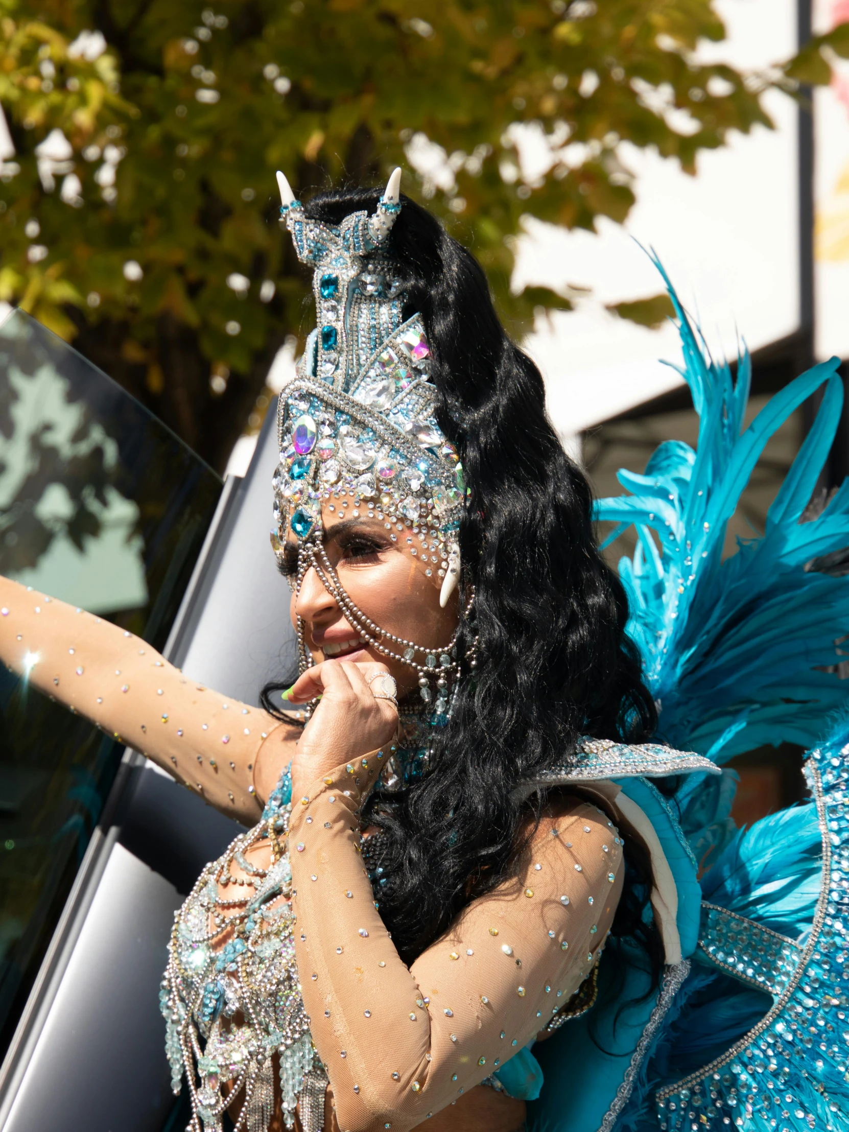 woman in a blue and silver dress, standing near a car