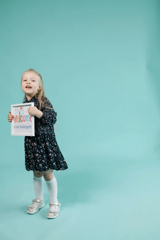 a small girl holding a sign against a green background