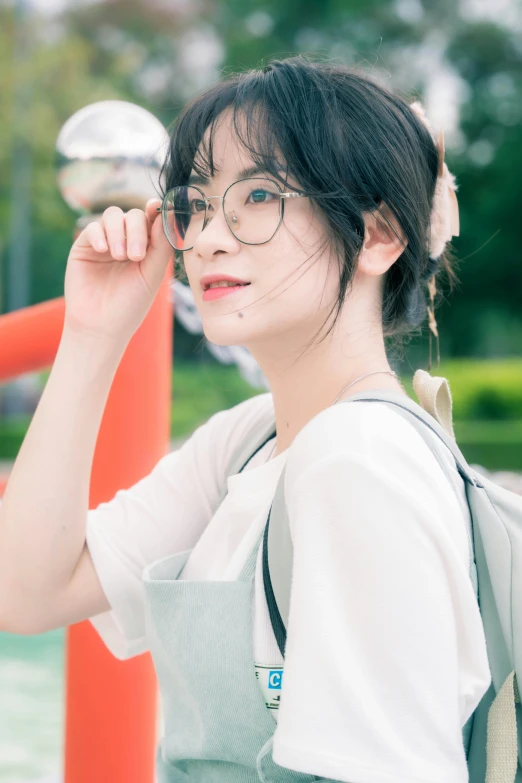 an asian woman looking back while holding up her eyeglasses