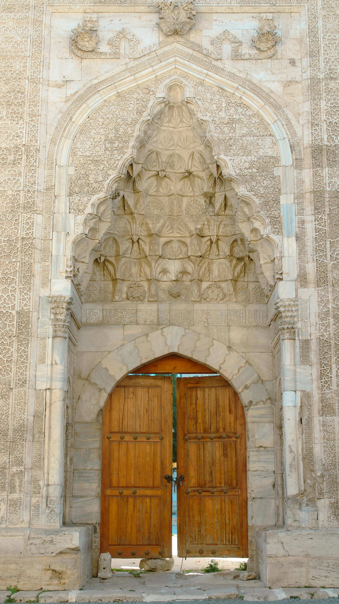 two large wooden doors in front of a white wall