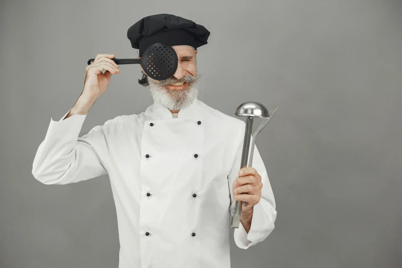 the chef holds two ladles and a whisk over his head