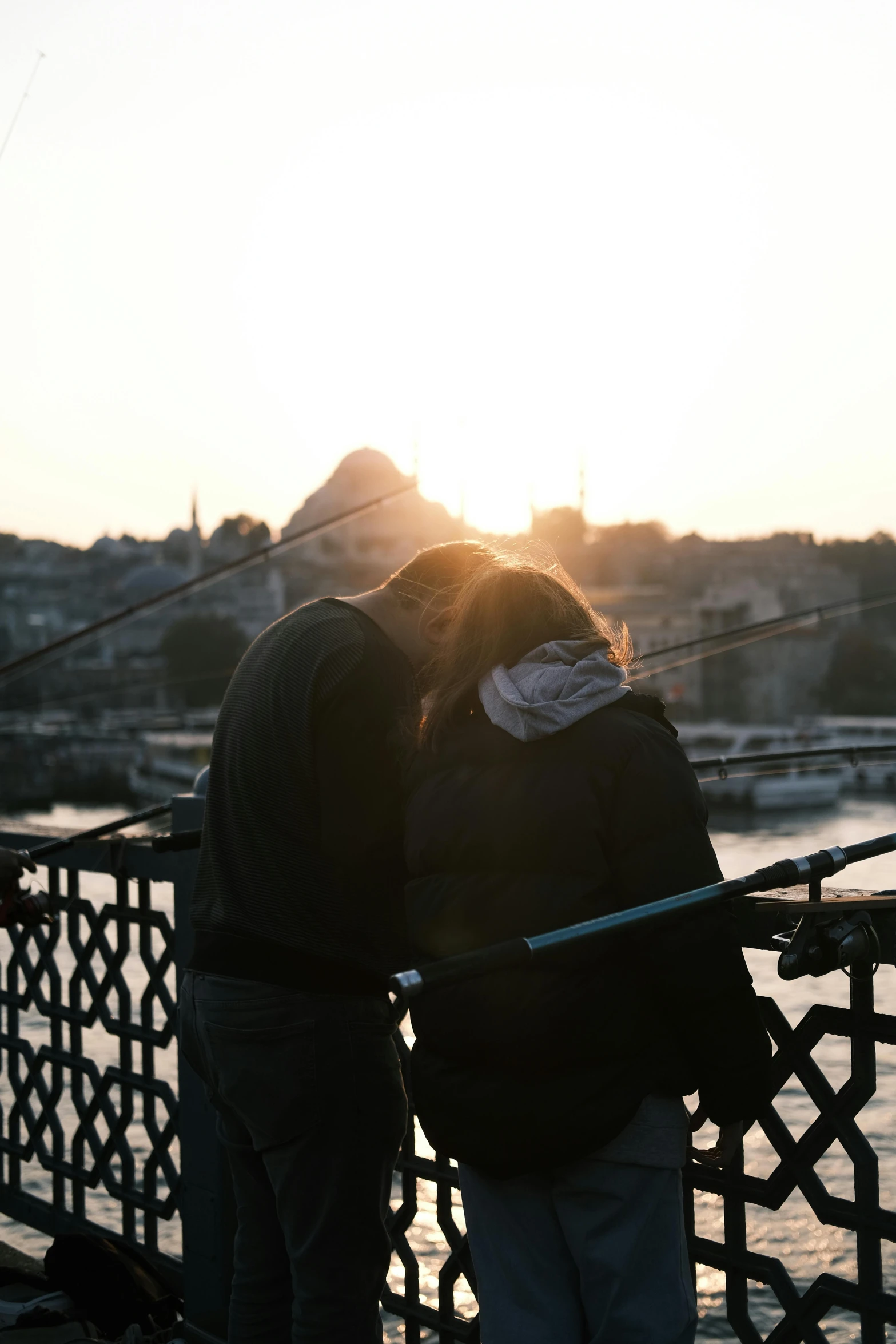 two people are standing on a pier next to the water