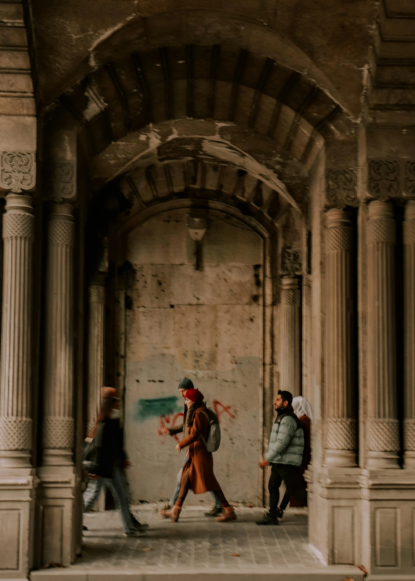 some people are walking by a wall with columns