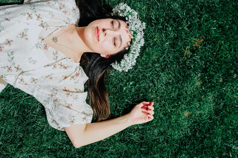 woman lying on grass, wearing bonnet, with eyes closed