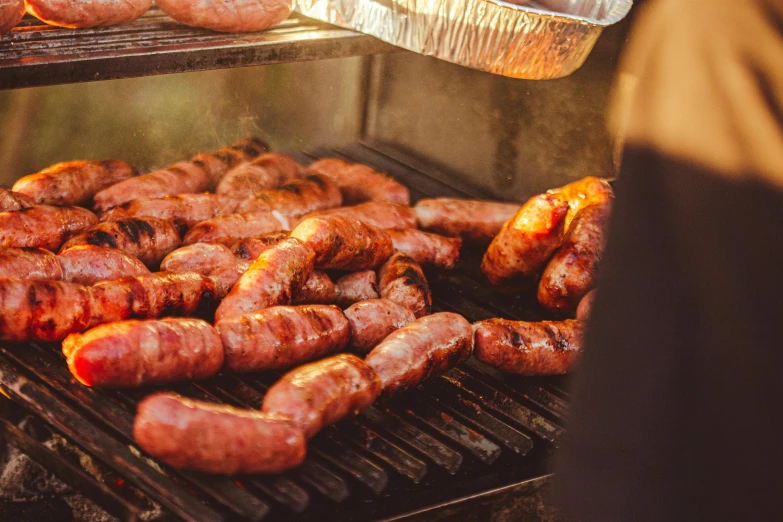 several sausages on an outdoor grill being prepared