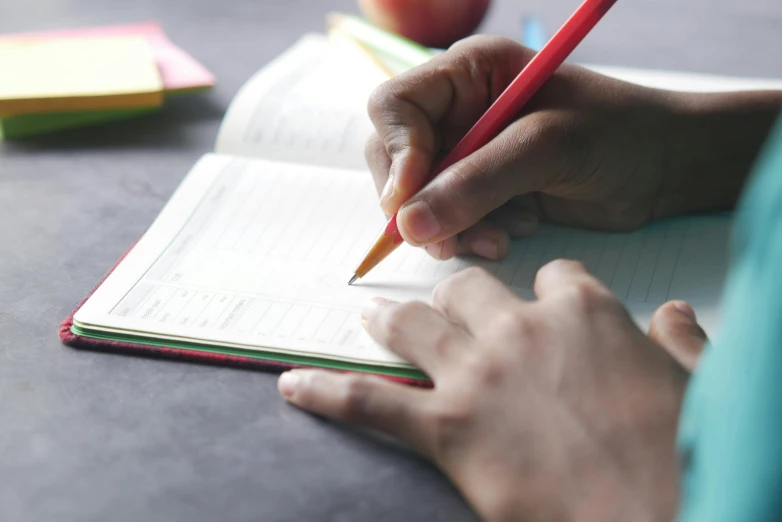 someone holding a pencil while doing homework