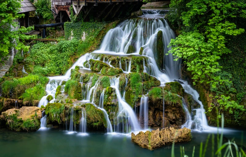 a beautiful waterfall is running over the green land