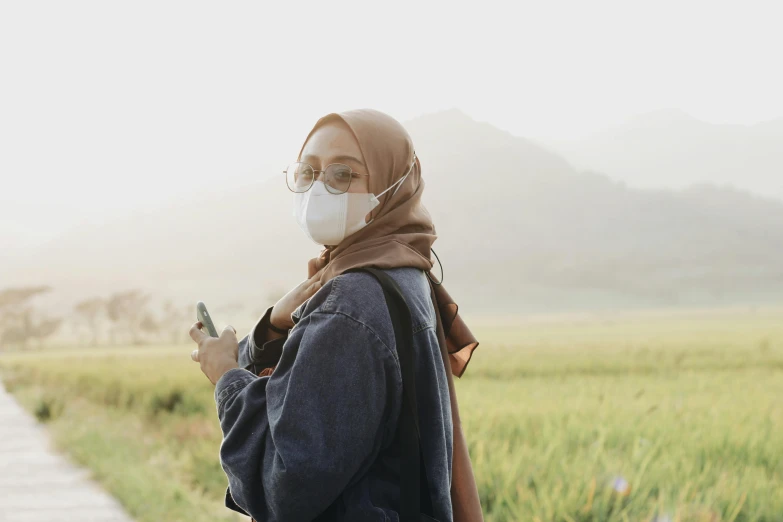 a young woman wearing a mask is looking at her phone