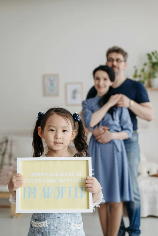 a mother and father holding up an i'm adopted sign