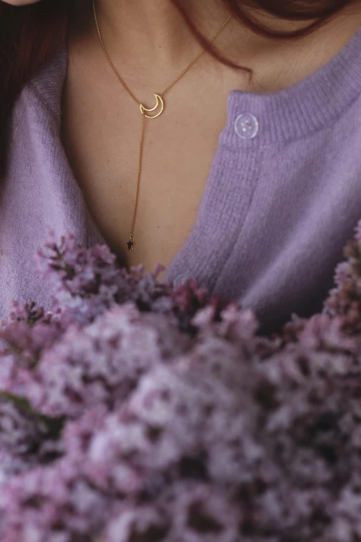 the girl is wearing her gold necklace with a crescent and pendant