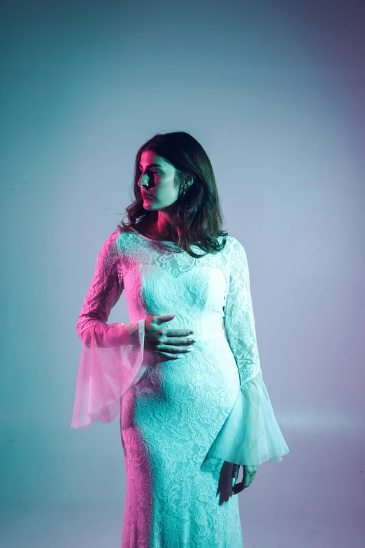 a pregnant woman in a long white dress and a pink veil