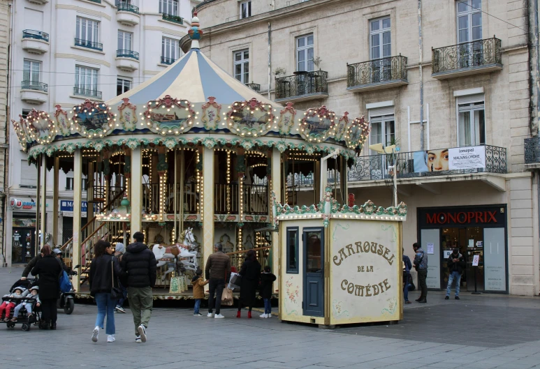 people stand near the merry go round outside an old building